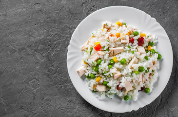 Chicken Breast with Rice and vegetables in white plate on Dark grey black slate background