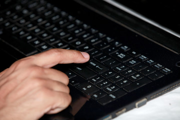 Human hand typing on laptop keyboard.