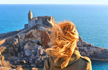 Young woman looks at San Pietro church with sea horizon in background, Lord Byron Natural park in...