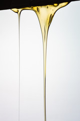 Pouring honey or golden liquid on white background.