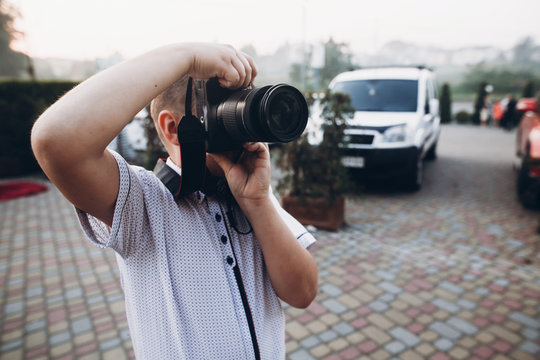boy holding big photo camera, playing as wedding photographer at wedding reception, photo booth