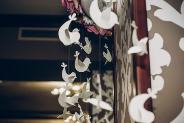 stylish roses decor at wedding reception in restaurant with paper birds