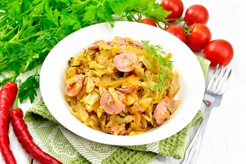 Cabbage stew with sausages in white plate on napkin