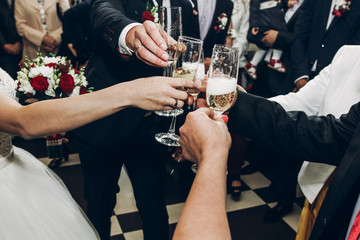 people toasting with champagne glasses at wedding reception, hands holding champagne drinks and...