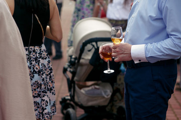 people toasting at wedding ceremony reception. guests holding champagne glasses. open bar in park, family and friends cheering with drinks