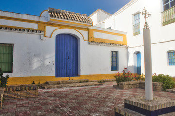 Spanish brightly colored courtyard or patio in the sun with an ornate cross on a column
