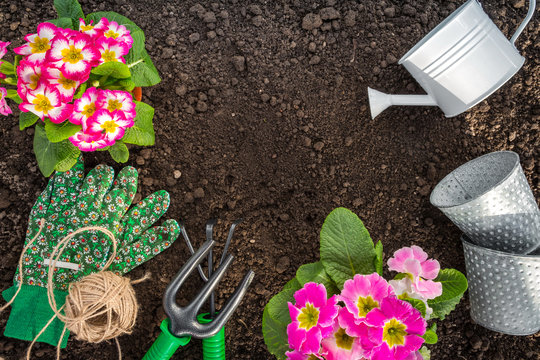 Gardening tools, hyacinth flowers, watering can and straw hat on soil background. Spring garden works concept. Horizontal layout with free text space captured from above (top view, flat lay)