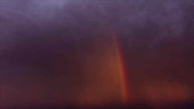 Cinematic storm clouds with rainbow and lightning strikes reflecting