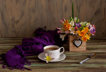 A cup with morning coffee and a bouquet of flowers freesia