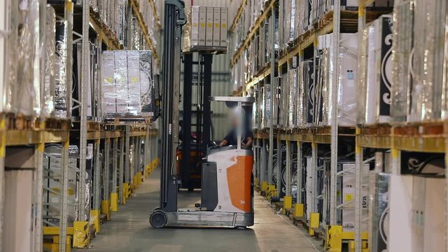 Large modern warehouse, forklift transports the box. Workflow in a warehouse with boxes