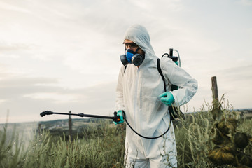 Weed control. Industrial agriculture theme. Man spraying toxic pesticides or insecticides on fruit...