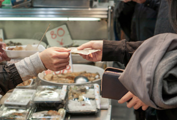 Closeup and crop of customer hands buy and pay Japan yen banknote for food in the market.