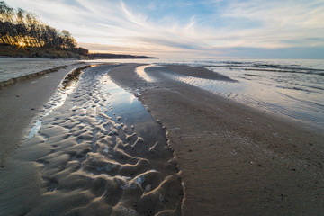 Bottom of the dried up stream on the shore of the Baltic Sea at sunset