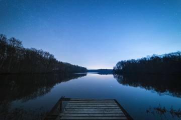 Small wooden pier in the calm lake at windless starry night