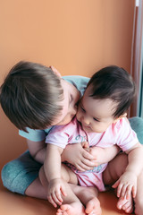 happy little brother playing hugs his sister baby, boy and girl embraces kisses, concept love and parenting