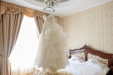 Bride's wedding dress hanging on a chandelier