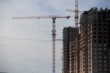 Construction of a multi-storey residential complex. Crane near the building under construction. Background construction site.