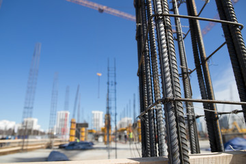 Concrete pillars on construction site. Building of skyscraper with crane, tools and reinforced...