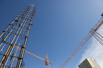 Fototapeta premium Concrete pillars on construction site. Building of skyscraper with crane, tools and reinforced steel bars.