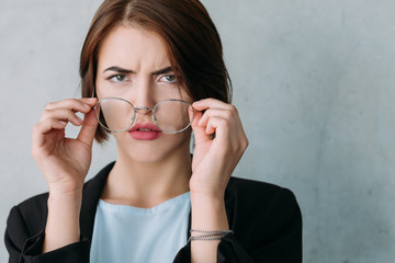 Closeup of young business lady looking confused, taking off glasses. Professional disagreement and disappointment.