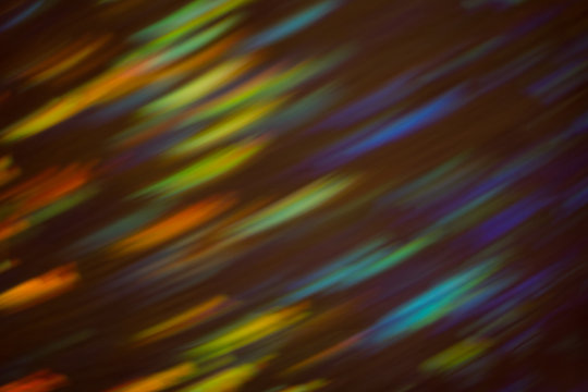 Glowing defocused lights on dark background. Blurred multicolor lines. Illuminated lens flare