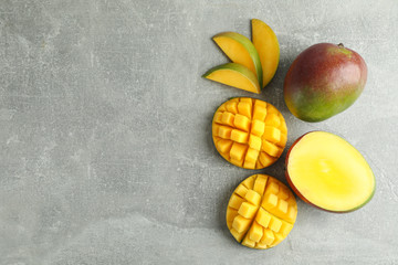 Flat lay composition with cut mangoes and space for text on grey background