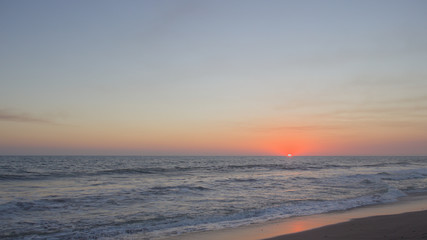 Fototapeta na wymiar Orange sun halfway disappeared into the ocean.