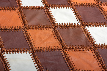 Pieces of multi-colored leather stitched with thread. Leather texture, background, haberdashery, sew clothes and bag.