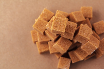 Brown cane sugar cubes on a light brown background
