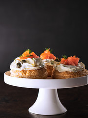 Smoked salmon tartlets snacks with cream cheese on a dark background with copy space. Spanish tapas.