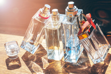 Fototapeta na wymiar Several bottles with perfume in rays of sunshine on wooden table