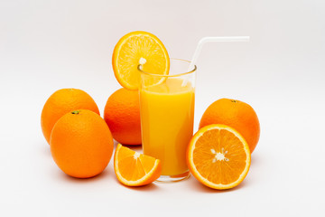 glass of orange juice and oranges on a white background