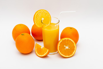 glass of orange juice and oranges on a white background
