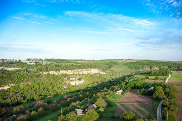 Fototapeta na wymiar Aerial view of green fields, farms, gardens and road by blue sky