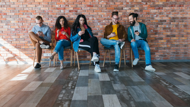 Millennials lifestyle. Group of young people phubbing coworkers, using smartphones. Information technology addiction.