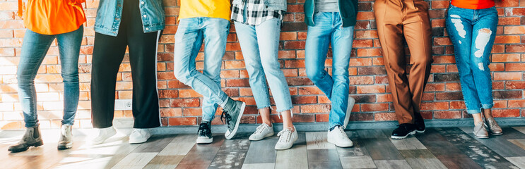 Millennials community. Cropped shot of young people in casual outfits standing against brick wall, socializing during break. - obrazy, fototapety, plakaty