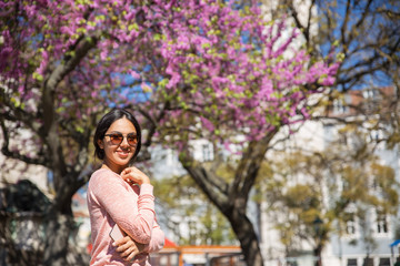 Happy woman posing at camera in front of blossoming tree