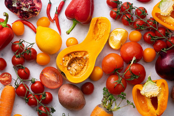 Flatlay with colorful vegetables arranged on white background. Sliced butternut squash, cherry tomatoes, bell peppers and carrots. Vegan nutrition concept