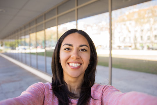 Happy young woman taking selfie photo outdoors