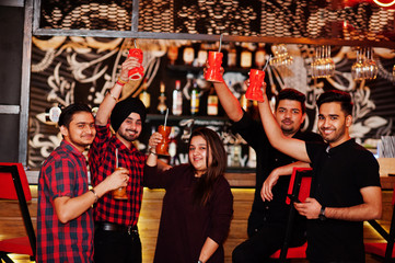  Group of indian friends having fun and rest at night club, drinking cocktails, clinking and cheers...