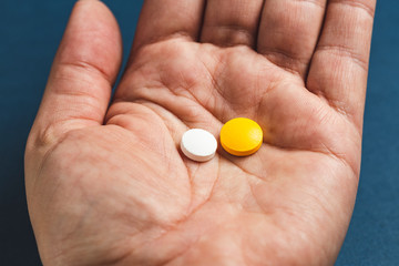 close-up view of a hand holding two pills