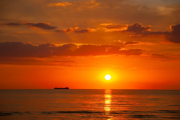 orange sunset on the sea with a ship on the horizon