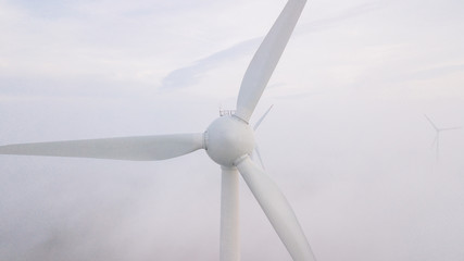 Windmills in the fog at sunrise. Wind turbine from aerial view. Sustainable development,...
