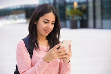 Content pretty student girl using smartphone