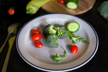 Fresh vegetables on white plate.  Broccoli sliced cucumbers and cherry/grape tomatoes. Organic vegetarian salad. 