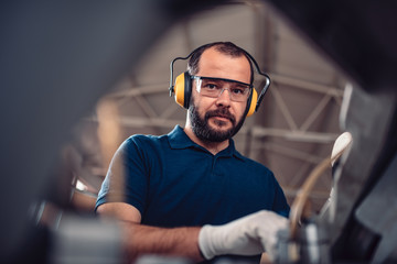 Factory worker operating band saw cutting machine