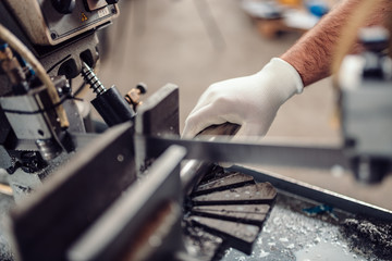 Factory worker operating band saw cutting machine