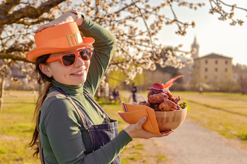 Girl with accessories for the holiday King's Day in the Netherlands, holding a bowl with donuts....