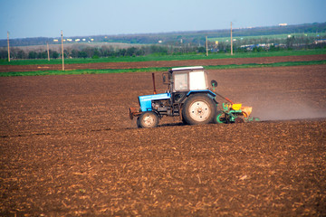 Obraz premium Tractor on the field and makes the fertilizer