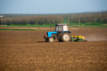 Obraz premium Tractor on the field and makes the fertilizer